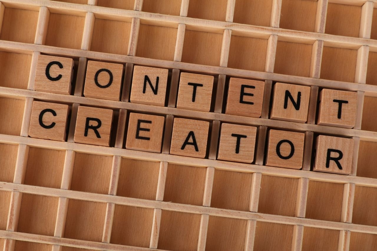 The Art of Drawing Readers In: Your attractive post title goes here Wooden block letters spelling 'Content Creator' on a grid background. Ideal for digital marketing themes.