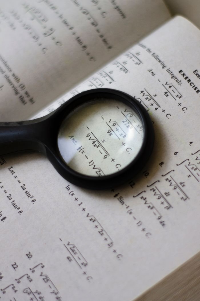 Crafting Captivating Headlines: Your awesome post title goes here A magnifying glass focuses on mathematical equations in a textbook, highlighting detailed calculations.