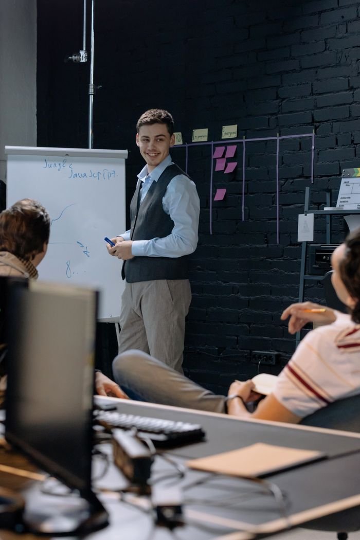 Services Young professionals discussing work in an office space while using a whiteboard for presentations and planning.